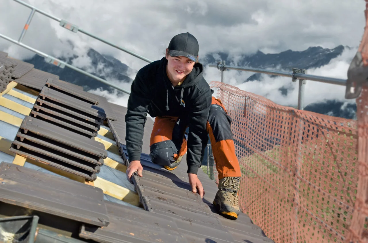 Dachdecker auf einem Dach beim Verlegen von Ziegeln.